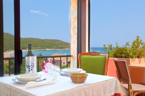 a table with a white tablecloth and wine glasses at Hotel Macchia e Mare in Pietracorbara