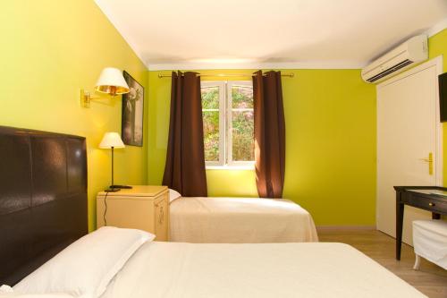 a yellow room with two beds and a window at Hotel Macchia e Mare in Pietracorbara