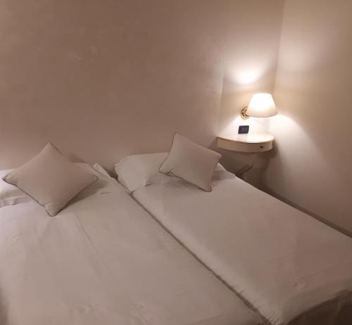 a white bed with two pillows and a lamp at Cà Doge in Venice