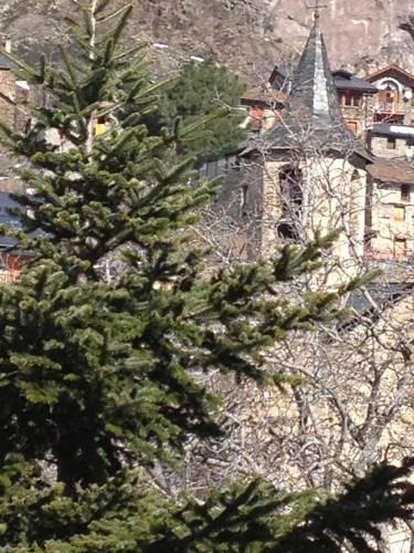 a pine tree in front of a church at Hotel Estanys Blaus in Tavascan