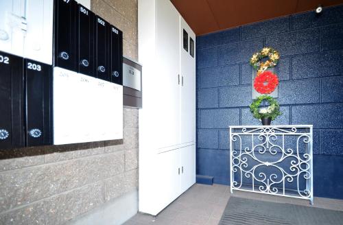 a room with a blue wall with a vase on a table at Apartment Zen Hotel in Mizuho