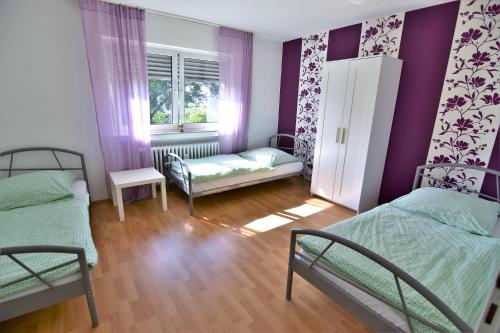 Habitación con 2 camas y ventana con paredes moradas. en Work & Stay Sankt Augustin mit Dachterasse en Sankt Augustin
