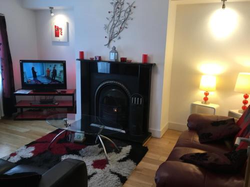 a living room with a fireplace and a tv at RossNua in Rosscarbery
