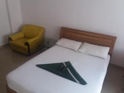 a bedroom with a bed with a chair and a book at Blue Stones Service Apartment in Coimbatore