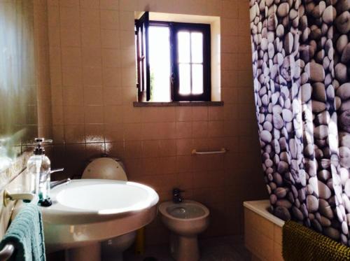 een badkamer met een wastafel, een toilet en een raam bij Studio Martins in Praia da Areia Branca