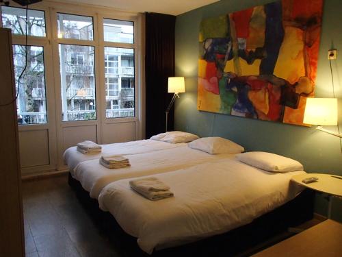 a bedroom with a bed and a painting on the wall at Bicycle Hotel Amsterdam in Amsterdam