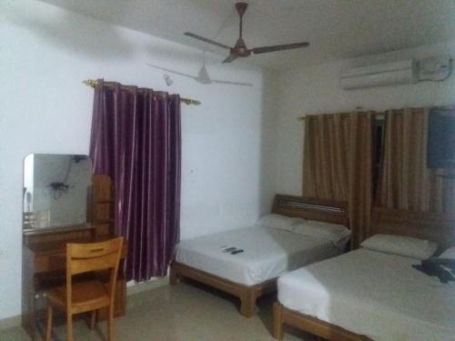 a bedroom with two beds and a table and a tv at Blue Stones Service Apartment in Coimbatore