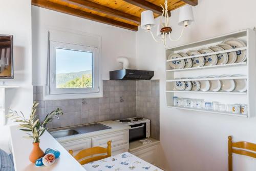 a kitchen with white cabinets and a table and a window at Villa Thea in Panormos Skopelos