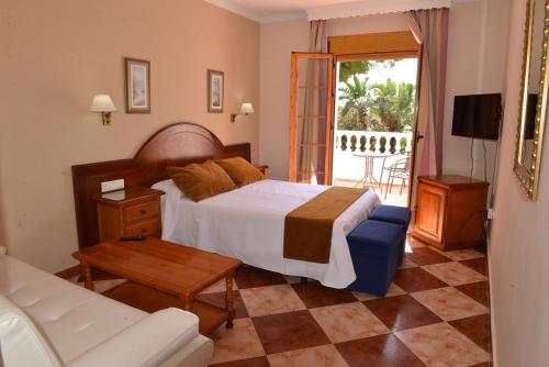 - une chambre avec un lit et un salon avec un canapé dans l'établissement Hostal Cabo Roche, à Conil de la Frontera