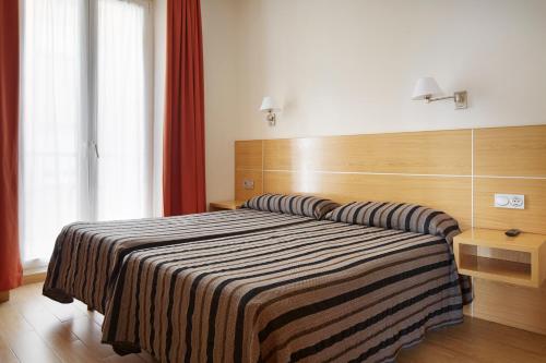 una camera da letto con un grande letto con una coperta a righe di Musika Plaza a Zarautz