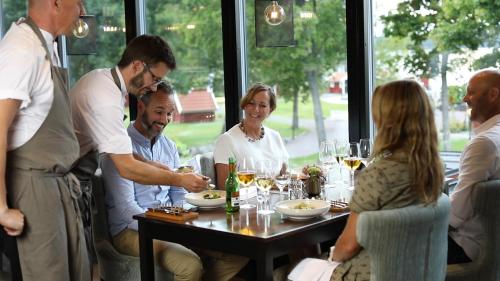 a group of people sitting around a table at a restaurant at Katrinelund Gästgiveri & Sjökrog in Stora Mellösa