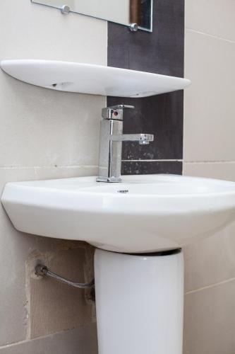 a white sink in a bathroom with a mirror at Résidences ASKÉ in Abomey-Calavi