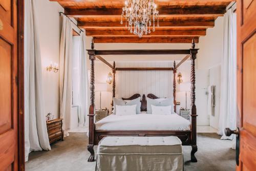 1 dormitorio con cama con dosel y lámpara de araña en Diamant Estate, en Paarl
