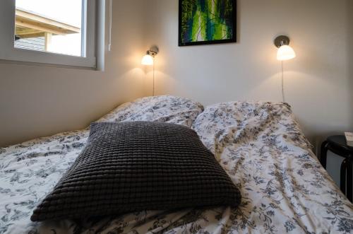 a bed with a pillow on it with two lights at Læsø Camping & Hytteby in Vesterø Havn