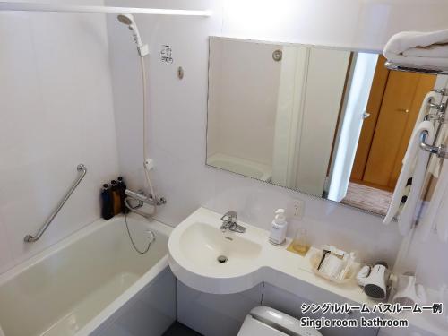 a bathroom with a sink and a tub and a mirror at Hiroshima Airport Hotel in Mihara