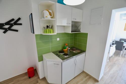 a small kitchen with white cabinets and green tiles at Meridiens in Dubrovnik