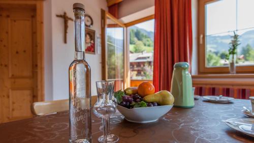 a bottle and a bowl of fruit on a table at Appartement Alpina in Alpbach