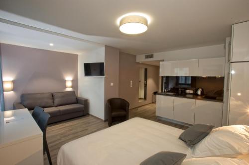 a bedroom with a bed and a kitchen and a couch at All Suites Appart Hôtel - Bordeaux - Pessac in Pessac