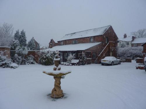 a snow covered yard with a bird bath in front of a house at RolandsCroft Guest House in Pontefract