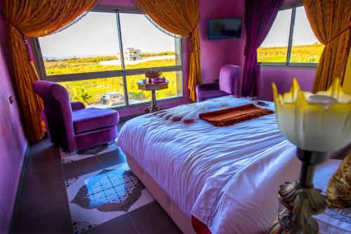 a bedroom with a bed and two chairs and a window at Maison d'hôtes La Ferme AZIZA in Fès
