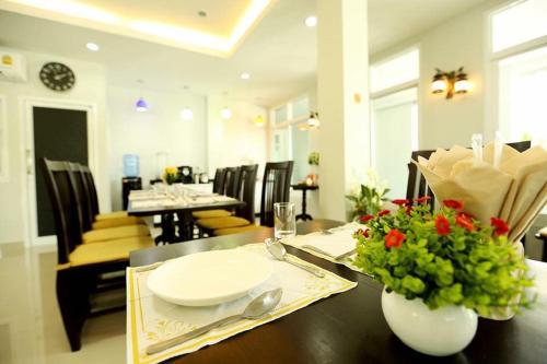 une salle à manger dotée d'une table avec des assiettes et des fleurs dans l'établissement Sirin Boutique, à Nakhon Ratchasima