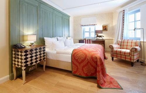 a bedroom with a bed and a desk and a chair at Relais & Châteaux Hardenberg BurgHotel in Nörten-Hardenberg