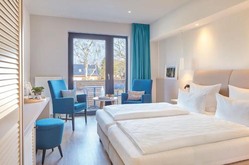 una habitación de hotel con una cama grande y sillas azules en Familotel Strandkind, en Pelzerhaken