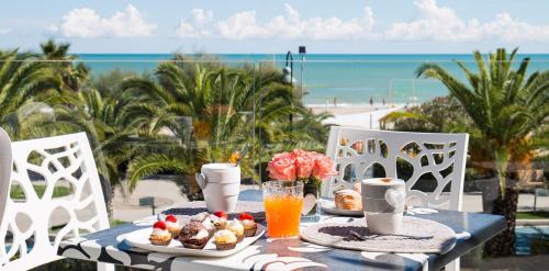 a table with food and a view of the beach at Hotel Excelsior in Alba Adriatica