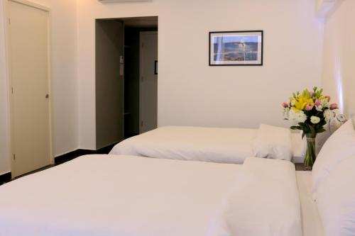 two beds in a room with a vase of flowers at Hamra Urban Gardens in Beirut