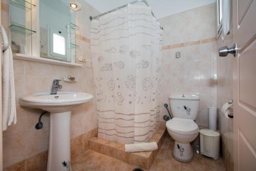 a bathroom with a sink and a toilet and a shower curtain at Contaratos Holiday Lettings 3 in Livadi