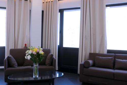 a living room with two couches and a table with flowers at Hamra Urban Gardens in Beirut