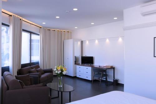 a living room with a couch and a desk with a television at Hamra Urban Gardens in Beirut