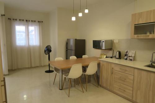 a kitchen with a wooden table and white chairs at AZ Pereybere Beach Apartment in Pereybere