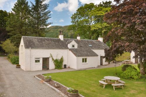 a white cottage with a picnic table in the yard at Melfort Village in Oban