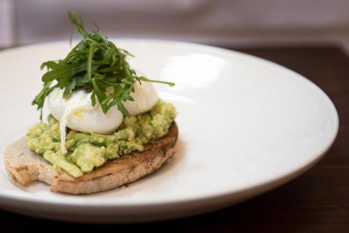 a white plate with a sandwich with mashed avocado and whipped cream at Briarfields Hotel in Titchwell