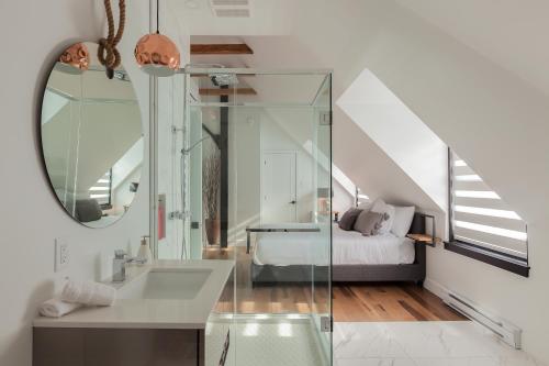 a bathroom with a sink and a bed and a mirror at Les Lofts Ste-Anne in Quebec City