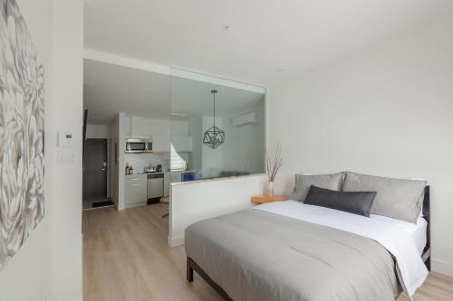 a white bedroom with a large bed and a kitchen at Les Lofts Ste-Anne in Quebec City