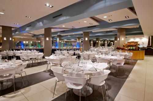 una sala da pranzo con tavoli e sedie bianchi di U Coral Beach Club Eilat – Ultra All inclusive a Eilat