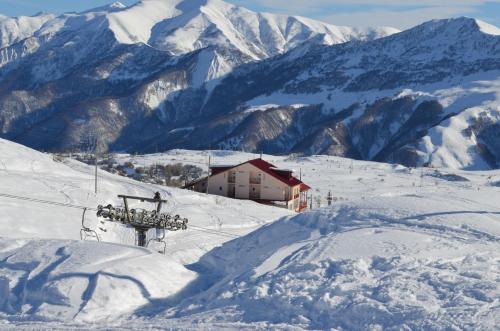 a ski lodge on a snowy mountain with snow covered mountains at Hotel Toni in Gudauri
