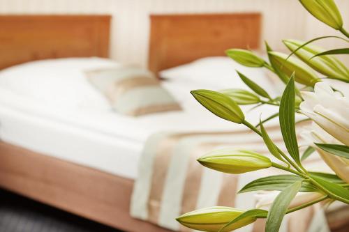 a bed with white sheets and a plant in the foreground at Rezydencja Solei Old Town in Poznań