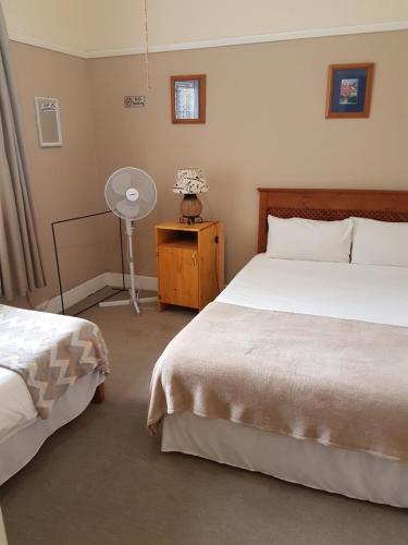 a bedroom with two beds and a table with a fan at Oasis Shanti Backpackers in Oudtshoorn
