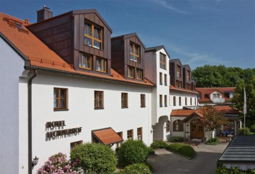 ein großes weißes Gebäude mit braunem Dach in der Unterkunft Hotel Lechnerhof Unterföhring in München