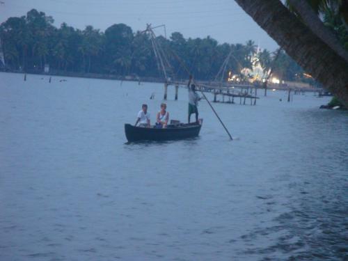 three people in a small boat in the water at West Wind Homez - Home Stay in Cochin