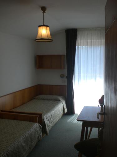 瓦雷那的住宿－Albergo Pensione Serenetta，酒店客房设有两张床和窗户。