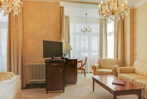 a living room with a tv and a couch at SEETELHOTEL Ahlbecker Hof das elegante Traditionshotel & ruhiger Rückzugsort an der Ostsee in Ahlbeck
