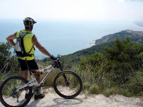 a man standing on a hill with a bike at Rustico del Conero in Camerano