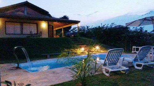 - deux chaises assises à côté de la piscine dans l'établissement Chácara Stefanini Atibaia com WIFI, à Atibaia