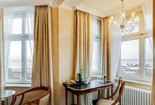 a dining room with a table and chairs and windows at SEETELHOTEL Ahlbecker Hof das elegante Traditionshotel & ruhiger Rückzugsort an der Ostsee in Ahlbeck