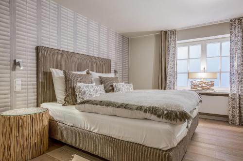 a bedroom with a large bed and a window at Apartmenthotel am Leuchtturm in Hörnum