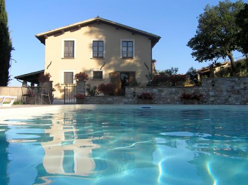 a villa with a swimming pool in front of a house at Genius Loci Country Inn in Bevagna